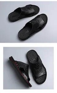 Detailed view of men's black slides featuring embossed crocodile texture and metal rivets.