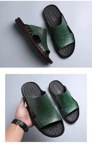 Close-up of men's green slippers with crocodile texture and metallic studs on black sole