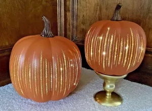 Detailed view of two orange starry night glass pumpkins displayed on a golden stand
