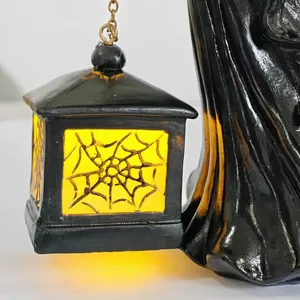 Detail van Halloween heksfiguurtje met een gloeiende LED-lantaarn met spinnenweb