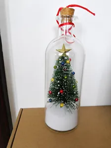 Miniature Christmas tree with ornaments inside a decorative glass gift bottle