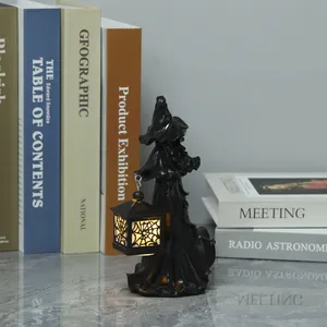 Detail van een zwarte hars heks figuur die een lichtgevende LED lantaarn vasthoudt