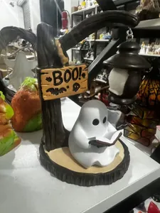 Close-up of a cute ghost figurine reading a book under a BOO sign lantern