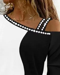 Primo piano di decorazioni in strass e spalline scoperte su un top a blocchi di colore.