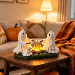 Detail of ghost figurines roasting marshmallows over a glowing campfire on a wooden table