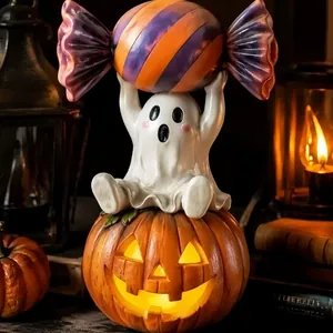 Statue de fantôme d'Halloween en résine sur une citrouille lumineuse tenant un gros bonbon.