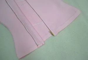 Vue macro détaillée de la fermeture éclair dorée sur un débardeur bandage rose