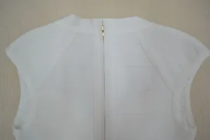 Vue détaillée du dos d'un haut bandage blanc sans manches avec une fermeture éclair dorée.