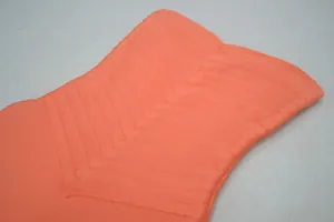 Détail macro du tissu bandage côtelé orange vif sur une robe bustier moulante.