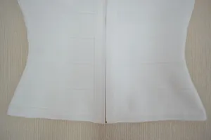 Gros plan d'un haut bandage blanc montrant le tissu élastique et le détail du zip.