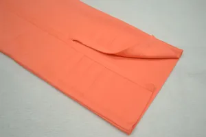 Gros plan sur l'ourlet fendu et le tissu côtelé d'une robe bandage rose corail