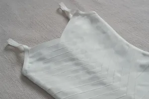 Gros plan du tissu d'une robe bandage blanche montrant le décolleté en V texturé et bretelles