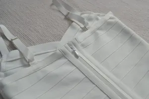 Gros plan d'une robe bandage blanche montrant la fermeture éclair et les bretelles fines.