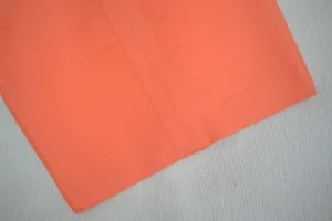 Gros plan sur la texture du tissu de la robe bandage orange vif extensible