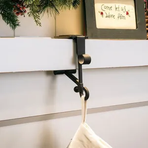 Gros plan d'un support de chaussettes de Noël en métal noir sur un rebord de cheminée.