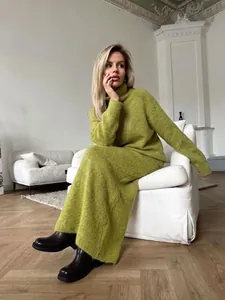 Model wearing olive green knit sweater and wide-leg pants set in modern living room.