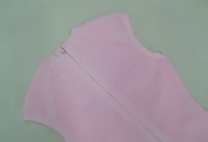 Detailopname van de verborgen rits aan de achterkant van een roze mouwloze bandagejurk