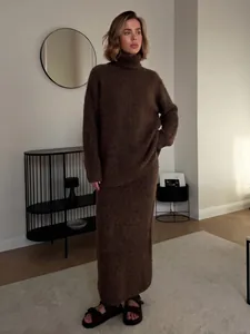 Model wearing a cozy brown wool blend knit sweater and matching long skirt in a modern interior