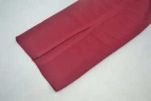 Detail van bordeauxrode bandagejurk met getextureerde stof en een split in de zoom.