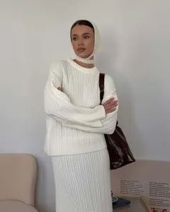 Model wearing a white ribbed knit sweater set with a matching headscarf and brown bag