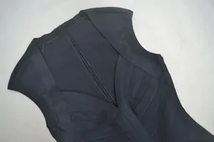 Detailopname van een zwarte mouwloze bandagejurk met geribbelde textuur en ritssluiting