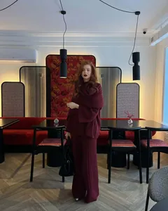 Full-body lifestyle view of model wearing a burgundy three-piece knit set in a cafe setting