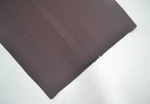Gros plan du tissu de robe bandage marron montrant la texture élastique épaisse