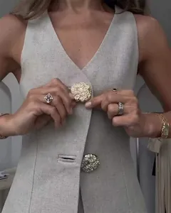 Close-up of elegant V-neck vest with textured gold buttons and linen fabric.