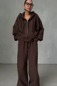 Close-up van vrouw in oversized donkerbruine hoodie met rits en wijde trainingsbroek