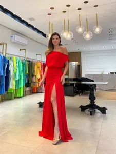 Full-length view of a red off-shoulder maxi dress with a thigh-high slit in a boutique.