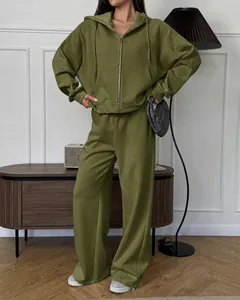 Detail van een olijfgroene oversized hoodie met rits en een bijpassende wijde broek voor dames.