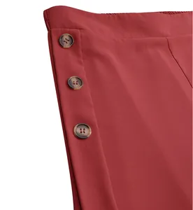 Detailed view of red high-waisted wide-leg pants featuring brown tortoiseshell buttons.