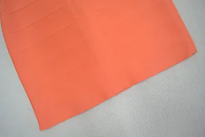 Vue détaillée du tissu de la robe bandage orange montrant des textures élastiques.