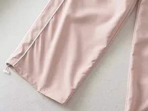 Detailopname van trekkoordsluiting en zijstreep op roze rechte sportbroek