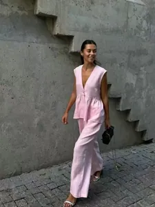 Elegant model walking in light pink sleeveless V-neck vest and wide-leg trousers set