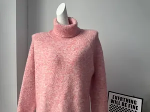 Close-up of a pink turtleneck wool blend knit sweater showing its soft fuzzy texture