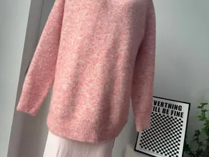 Detailed texture shot of soft pink wool blend melange knit sweater in a cozy setting