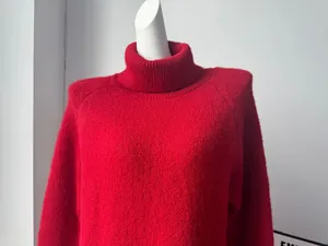 Detailed view of vibrant red wool blend knit turtleneck sweater on white mannequin torso