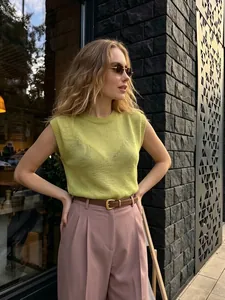 Outdoor lifestyle detail shot of a lime green sleeveless knit top with pink trousers