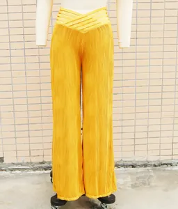 Detail view of yellow high-waisted wide-leg trousers with wavy pleats on a mannequin form