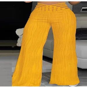 Close-up detail of high-waisted yellow wide-leg pants with wavy pleated texture and cutouts