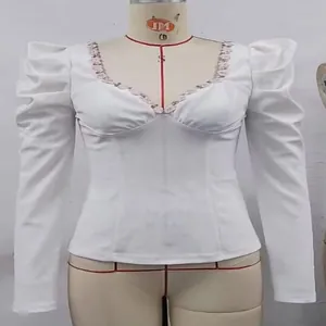 Close-up detail of white long sleeve top with puff shoulders and floral lace V-neck