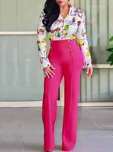 Detalle de los pantalones magenta de talle alto con botones dorados de doble botonadura