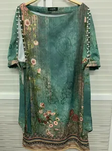 Detailansicht des ethnischen Blumendrucks und der Perlenstickerei auf dem grünen Kleid