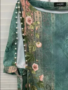 Detail eines Kleides mit Blumendruck und eleganten Perlenverzierungen am Ärmelrand