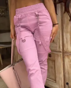 Detail of pink cargo pants with vintage pockets, decorative metal rings and straps