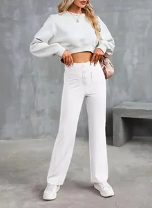 Close-up full view of white high-waisted trousers featuring elegant button details.