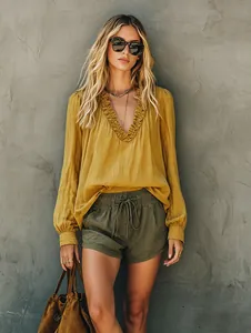 Detail of a casual yellow V-neck ruffle blouse with long sleeves and light texture.