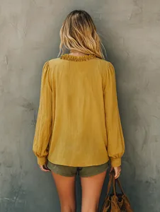 Detailed back view of a mustard yellow relaxed long-sleeved blouse with ruffled collar.