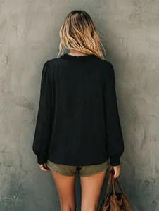 Back view of a black long-sleeved shirt with ruffled collar and textured fabric.